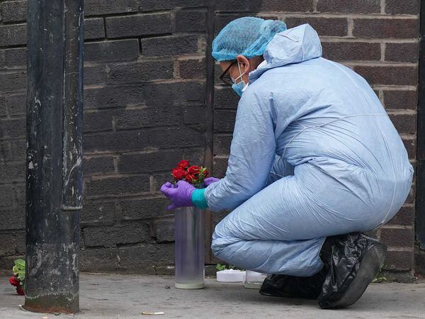 A forensic investigator puts flowers into a container at the scene near the Whitgift shopping centre