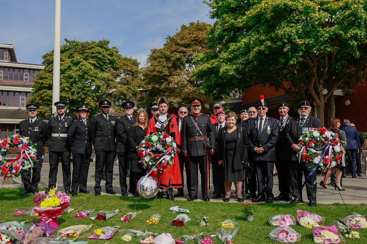 Dignitaries, council officials and members of the armed forces pose by the tributes. Photo: Ben Gregory-Ring