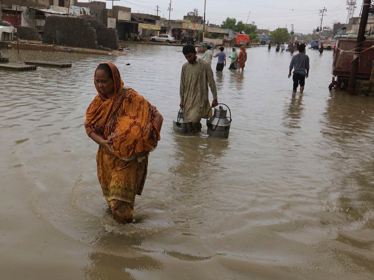 Local residents wade through flooded area caused by heavy monsoon rains in Karachi, Pakistan