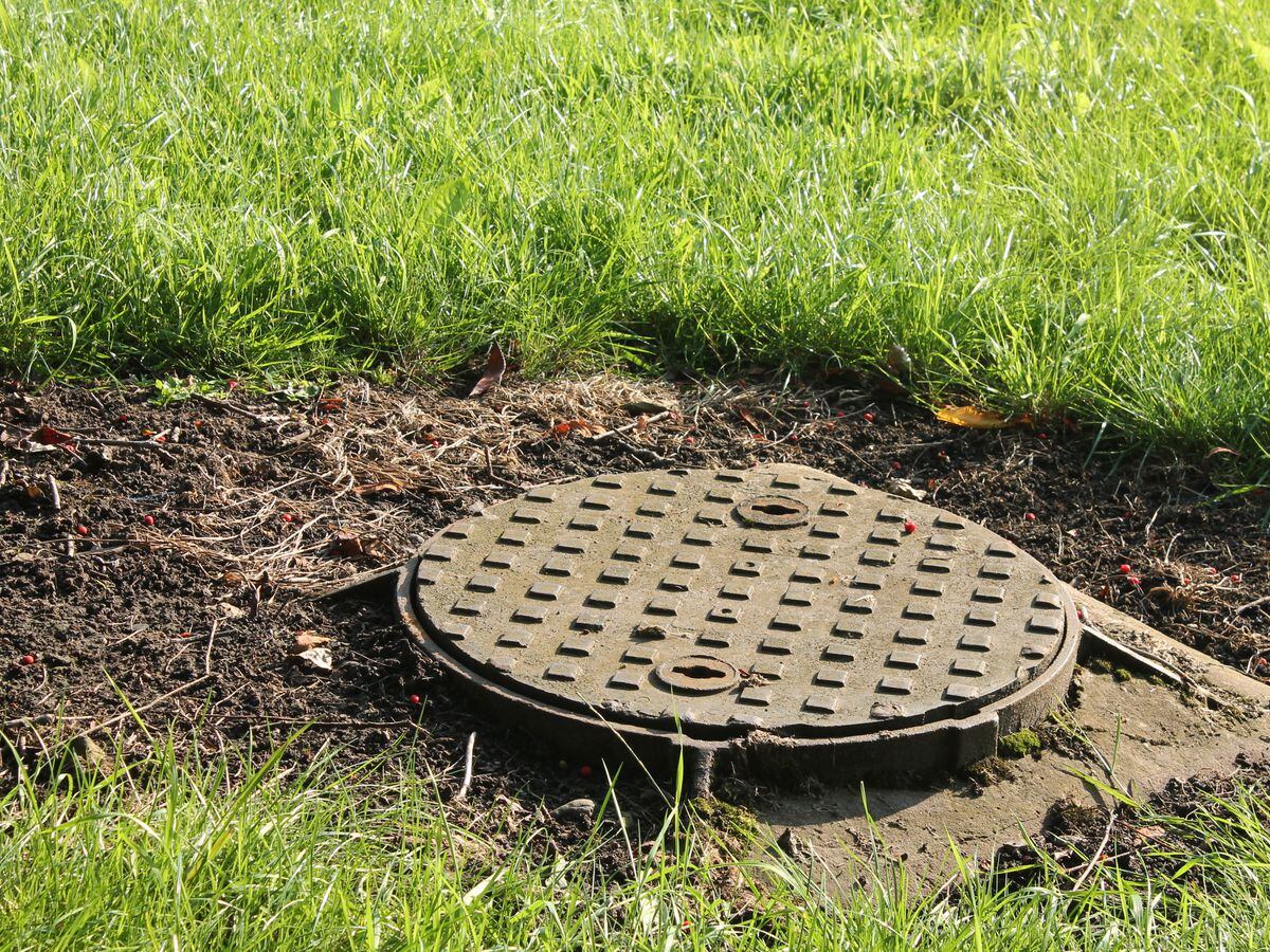 Round metal manhole cover surrounded by grass