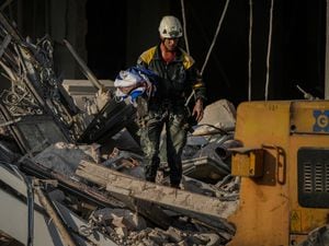A member of a rescue team recovers a Cuban national flag at the site of a deadly explosion
