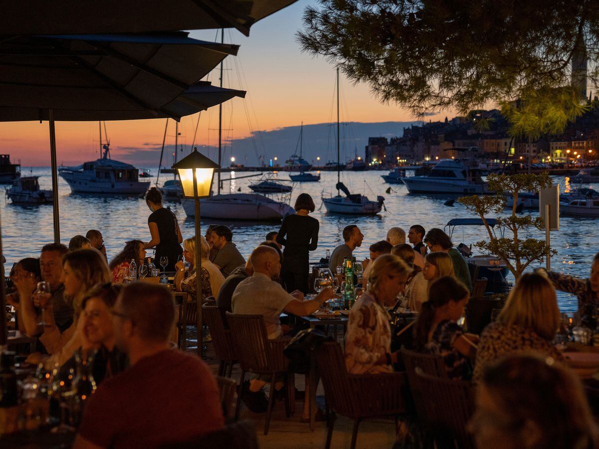 Des vacanciers sont assis dans un restaurant en bord de mer, dans la ville adriatique de Rovinj, en Croatie (Darko Bandic/AP)