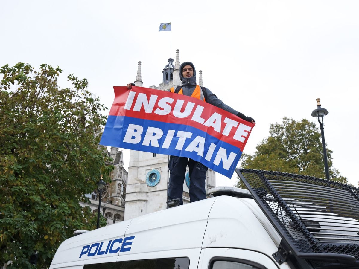 A protester from Insulate Britain stands on a police van