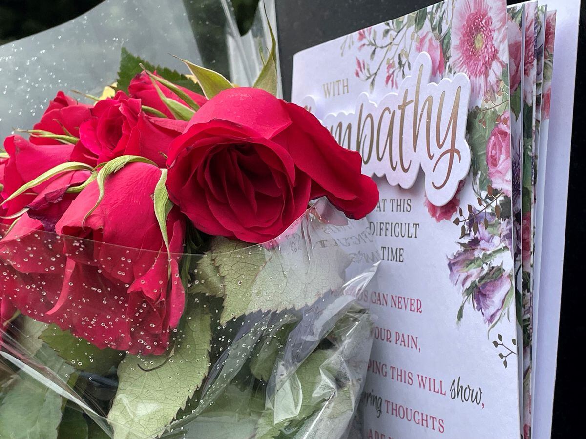 Flowers and a card left on signage outside the remains of The Crooked House pub near Dudley 