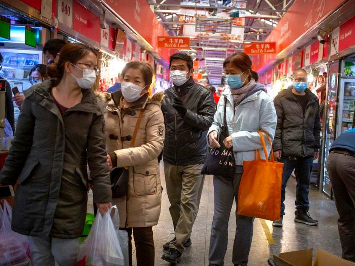 People wear face masks as they shop at a market in Beijing