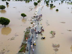People walk through floodwaters after heavy rainfall in Hadeja, Nigeria, Sept 19, 2022