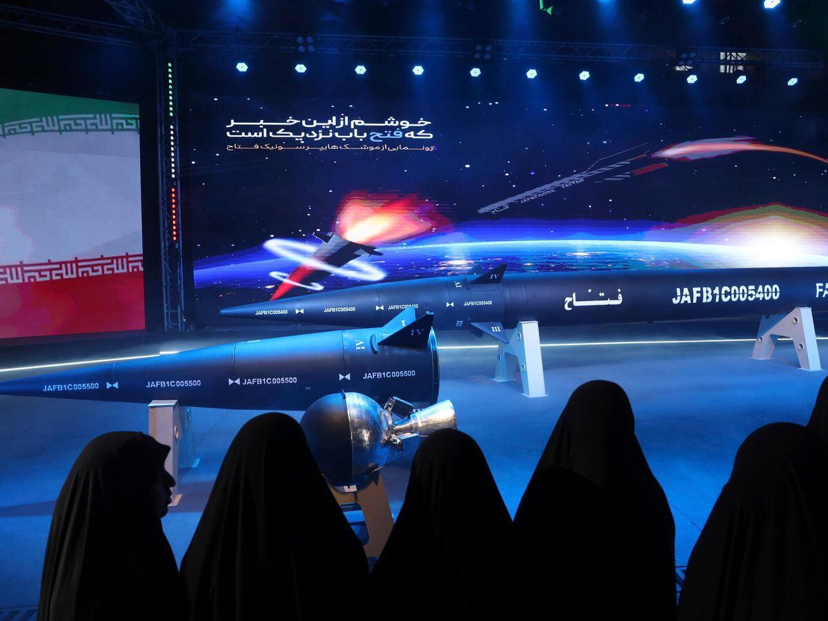 Women look at the Fattah missile at a ceremony in Tehran, Iran