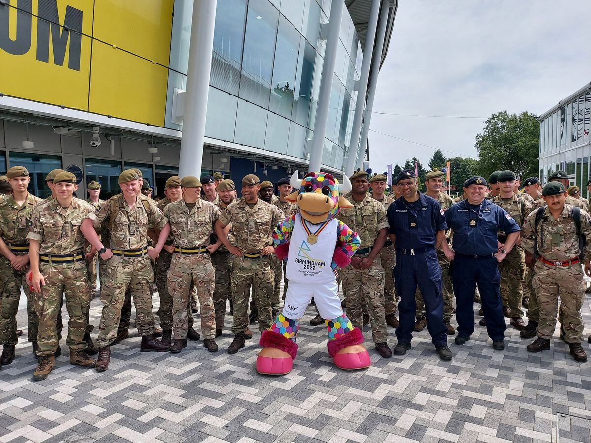Games mascot Perry poses with some of the many forces personnel working at the Games