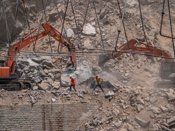 Rescue workers run for cover as earth movers dig through rubble of a collapsed tunnel in Ramban district, south of Srinagar, Indian controlled Kashmir, on Friday May 20 2022