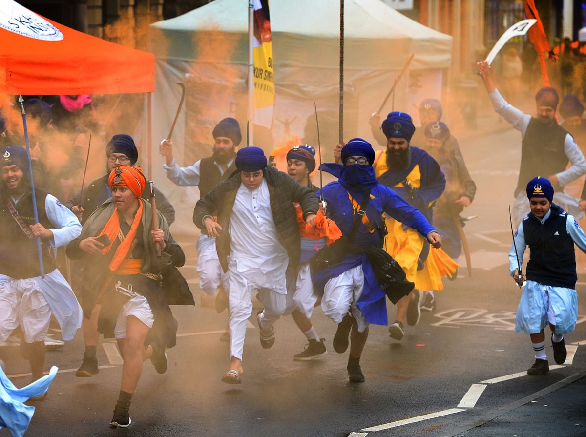 Members of Gatka teams run down Smethwick High Street with colourful flares