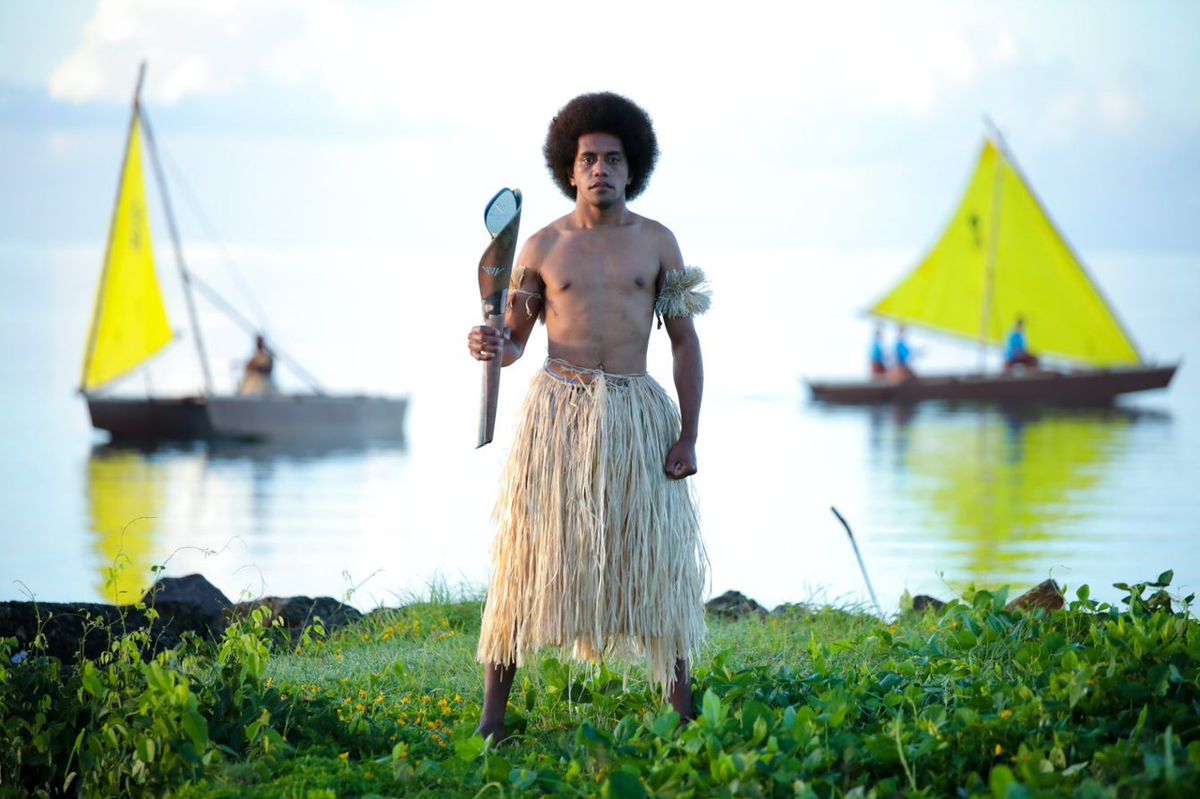 A local man in traditional grass skirt holding the Baton as it visits Fiji