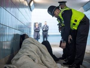 A stock image of police speaking with people in an underpass. 