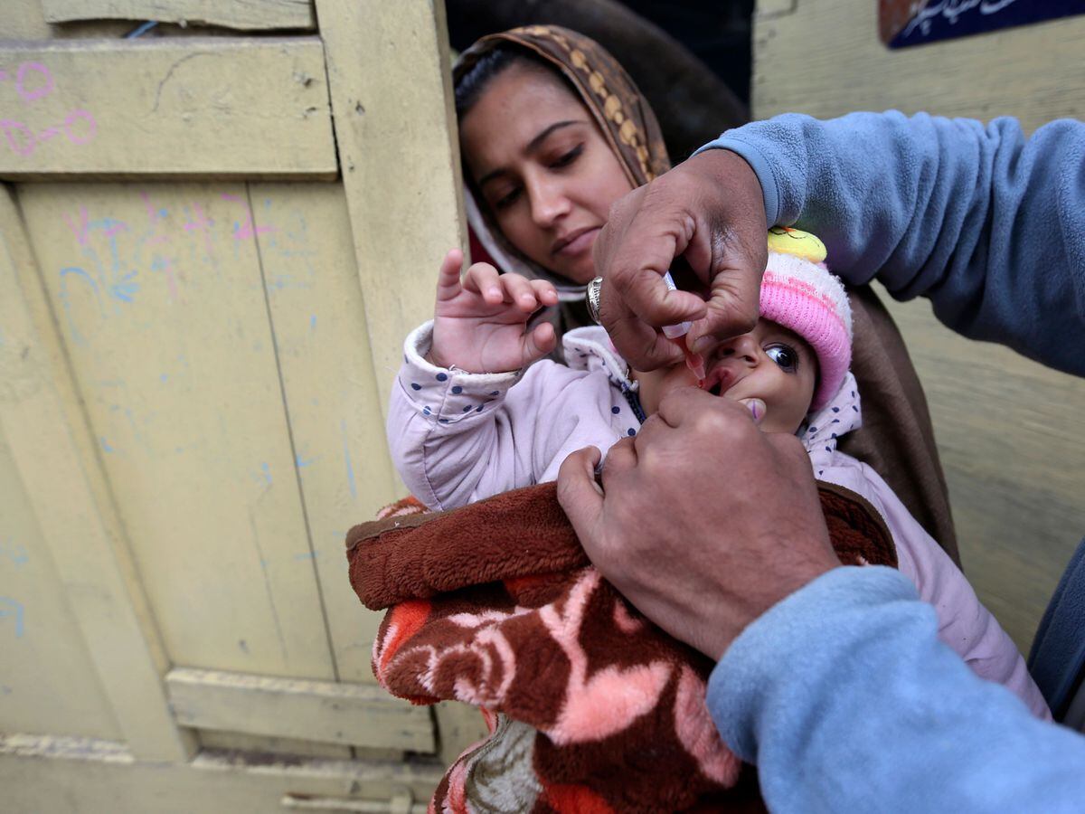 A health worker administers a polio vaccine to a child in Lahore, Pakistan (KM Chaudary/AP)