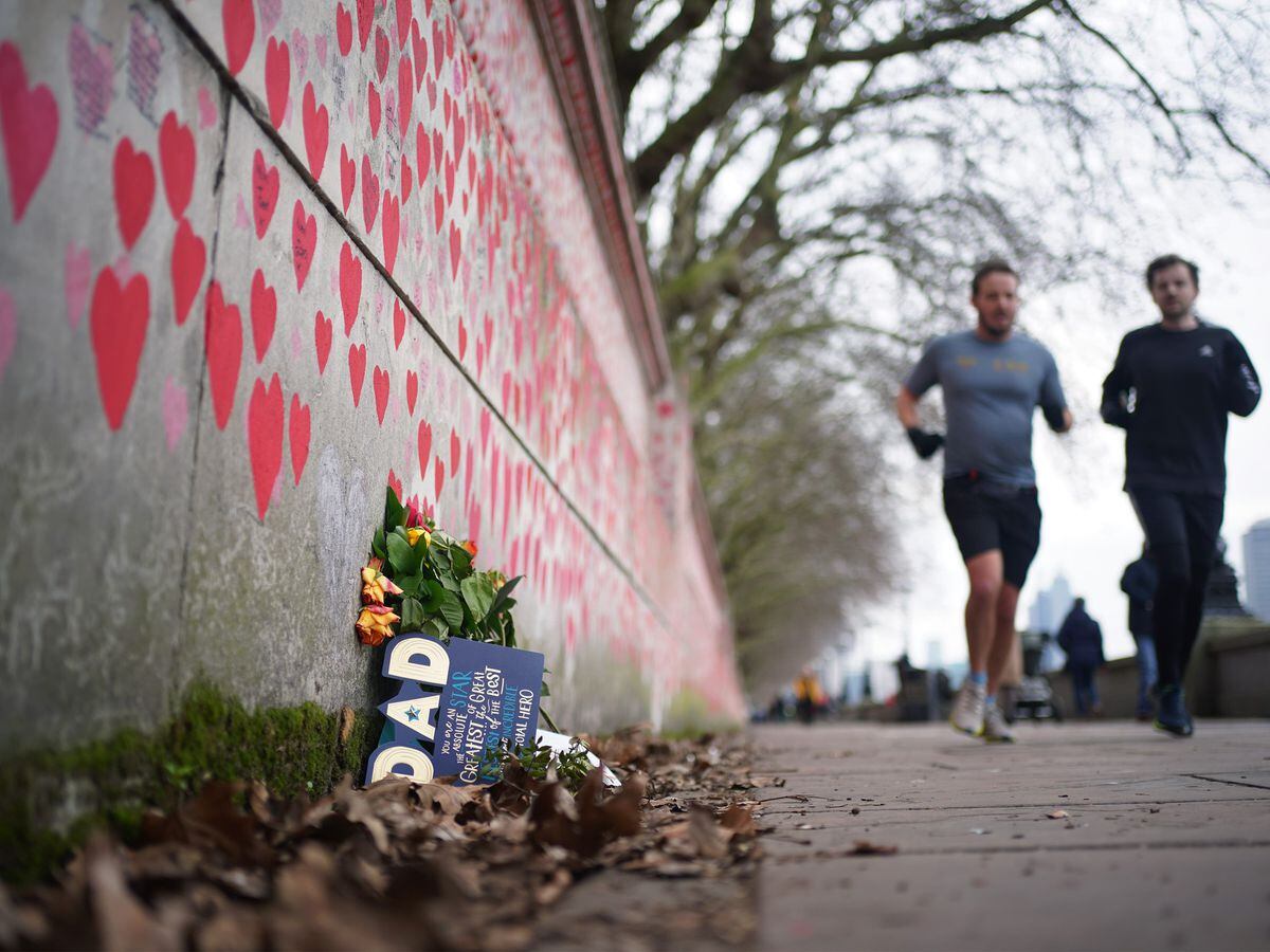 People jog past the Covid memorial wall in central London