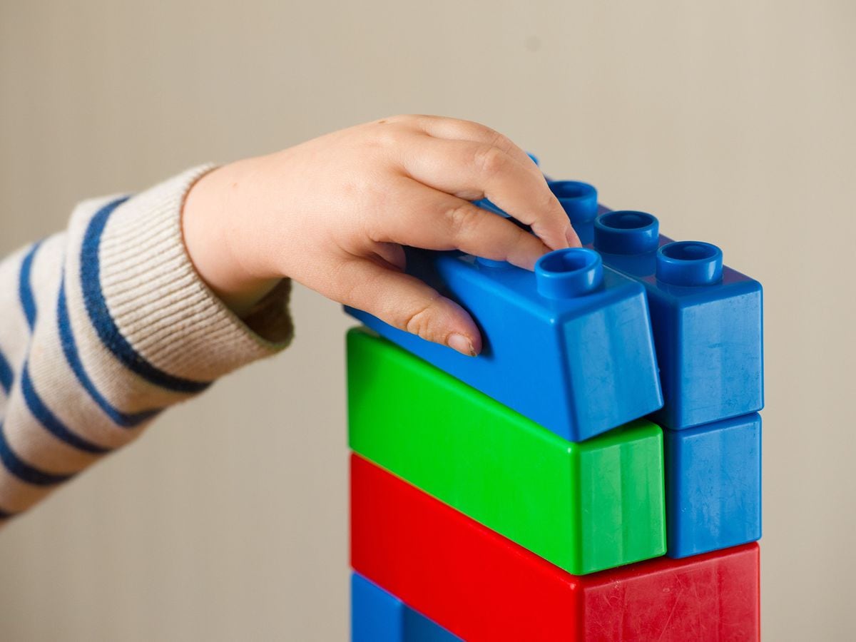 A preschool age child plays with plastic building blocks