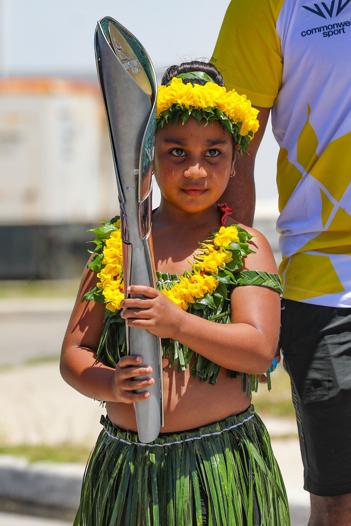 A child in a traditional grass skirt holds the Baton in Nauru