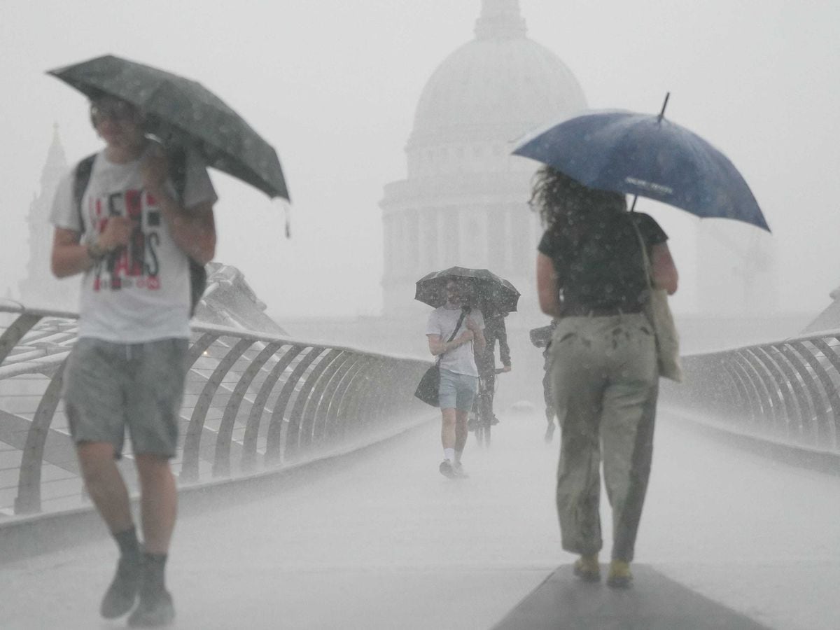 People with umbrellas walking in the rain on Millennium Bridge