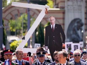 People hold a picture of Russian President Vladimir Putin and a letter Z during the Victory Day ceremony in Belgrade, Serbia, on Monday May 9 2022