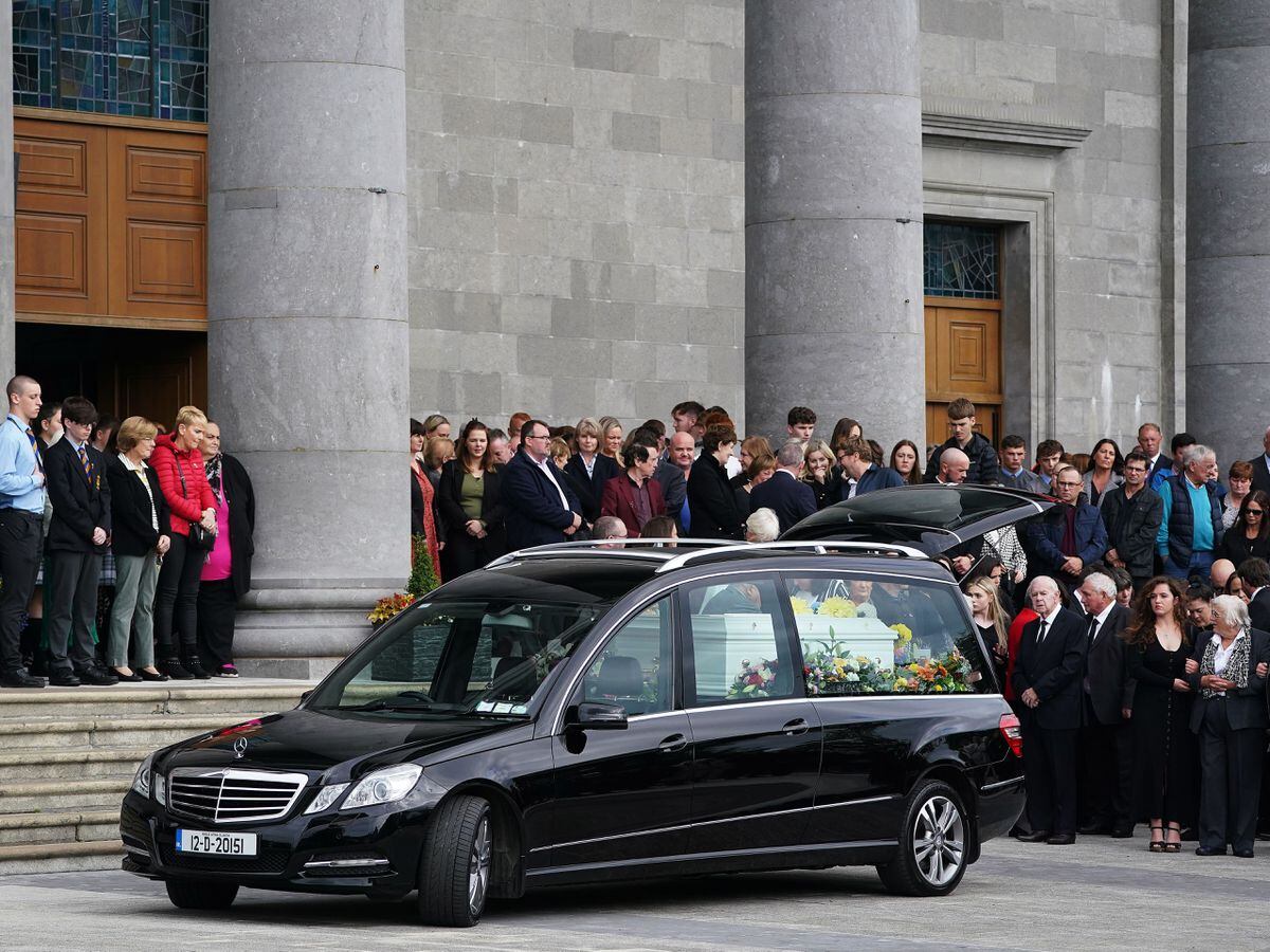 Mourners gather behind the hearse carrying the coffin bearing the remains of Mikey and Thelma Dennany in Longford, following their funeral Mass