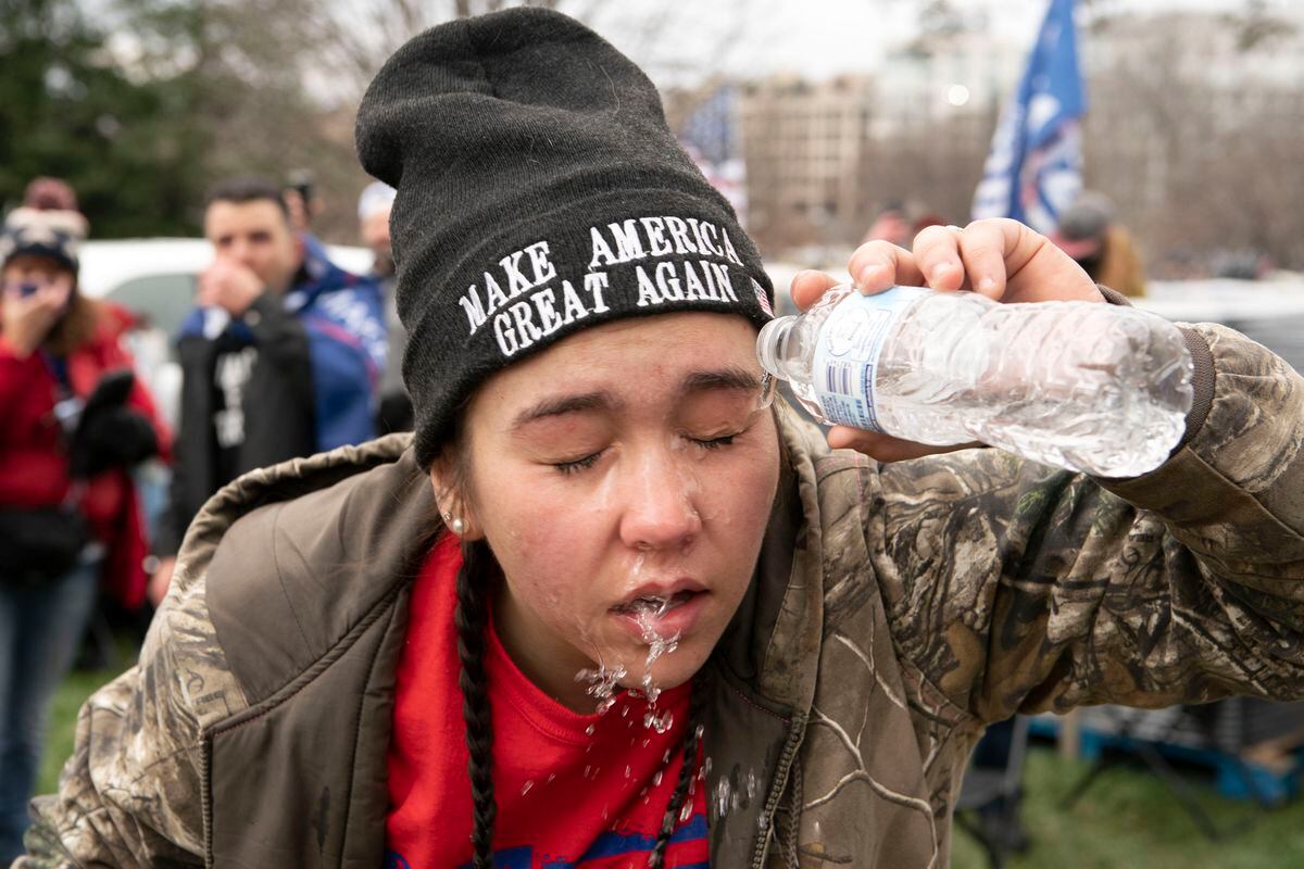 A supporter of President Donald Trump puts water in her eyes after U.S. Capitol Police officers deployed tear gas at demonstrators outside of the U.S. Capitol on Wednesday, Jan. 6, 2021, in Washington. (AP Photo/Jose Luis Magana)            