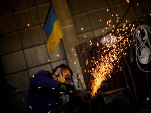 A volunteer shapes metal plates with an angle grinder at a facility producing material for Ukrainian soldiers in Zaporizhzhia, Ukraine