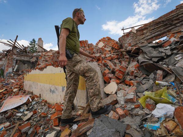 A Ukrainian serviceman looks at the rubble of a school that was destroyed some days ago during a missile strike in outskirts of Kharkiv, Ukraine