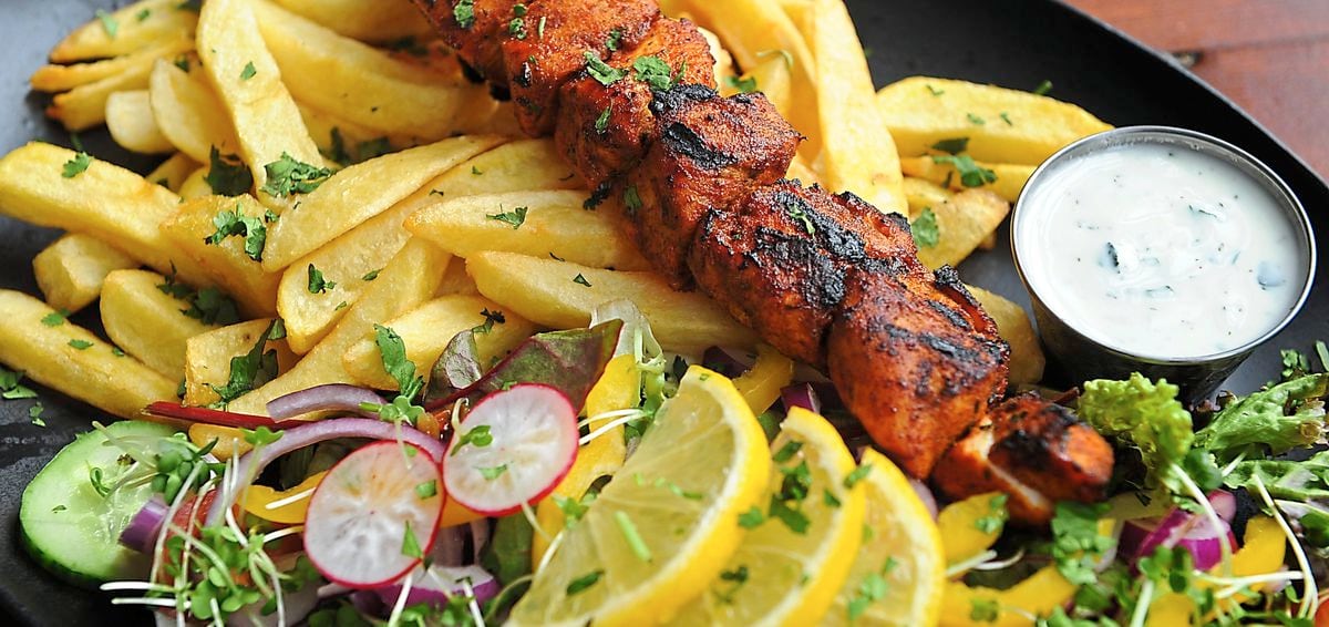 Juicy chicken tikka skewer with mint raita, onion salad and chips hit the spot