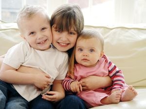 Three children in close embrace, girl aged 8 to 10 years, boy aged 3 to 4 years, baby girl aged 6 to 12 months