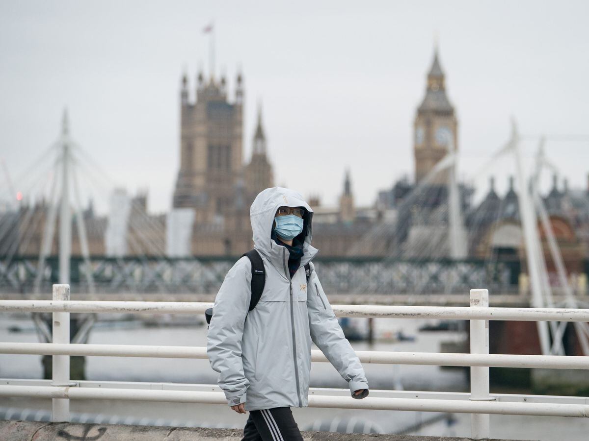 A person wearing a face mask crosses Waterloo Bridge, in London