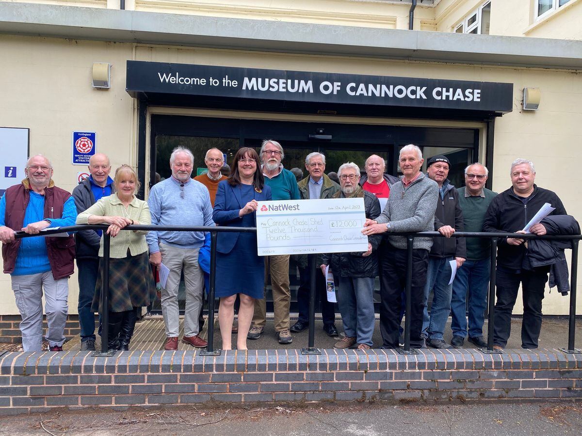 Receiving the cheque from Jo Walker Crematorium Manager outside The Museum of Cannock Chase where the members meet every Monday. From left to right: Colin Mann, Philip Sanders, Nita Deacon, Tony Lyons, Leslie Jewkes, Jo Walker, David Causer, Ray James, Bill Read, David Pursall, Barry James, Mick Steventon, Graham Johnson, Bryan Banks.