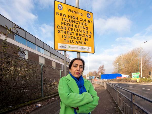 Councillor Jasbir Jaspal with the High Court Injunction Street signage in Bilston