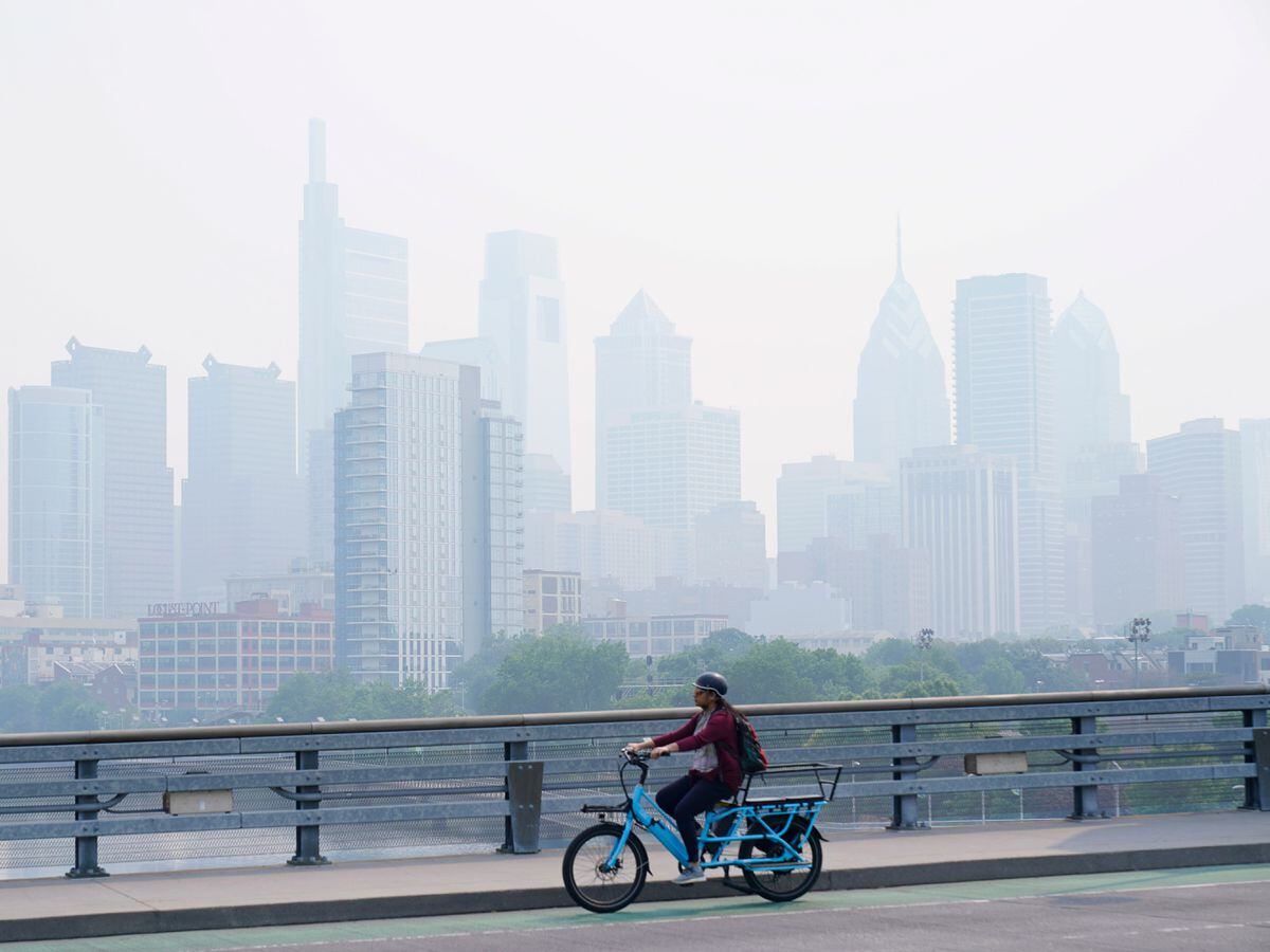 A person cycles past the skyline in Philadelphia shrouded in haze