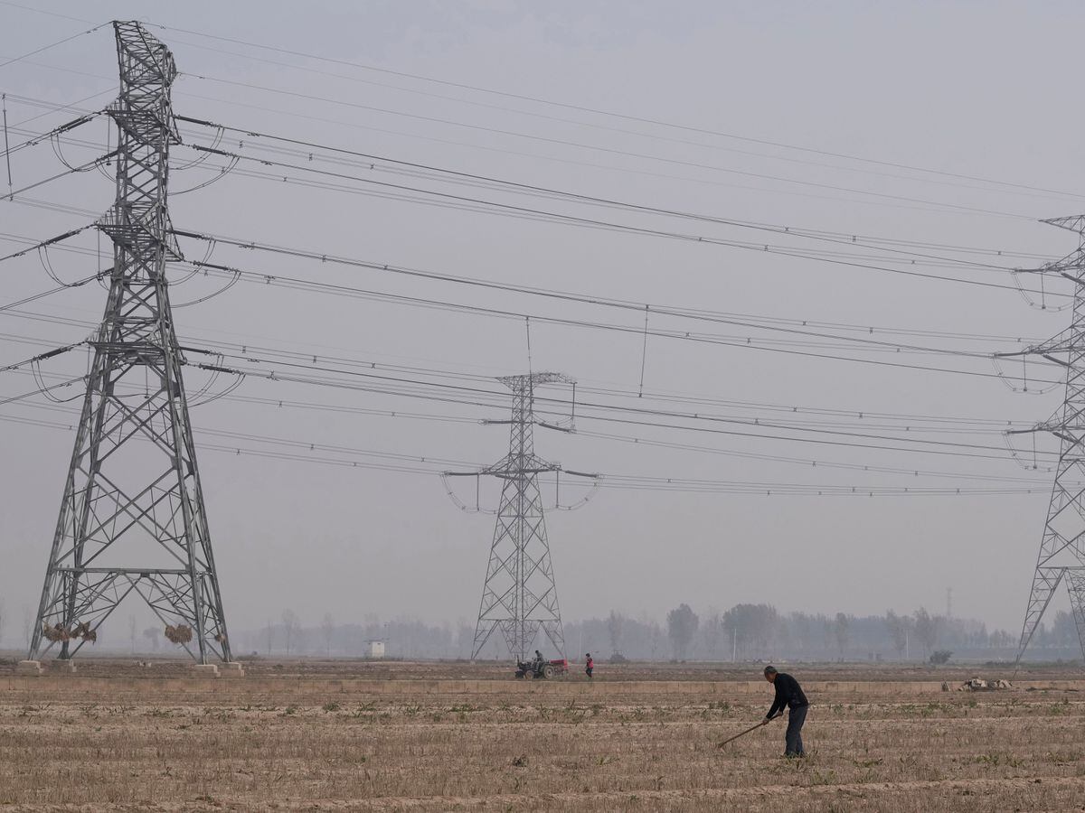 A farmer tills his land under power lines near central China’s Henan province