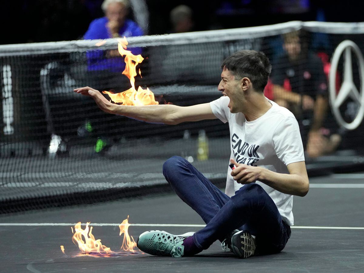 A protester lights his arm on fire on the court on day one of the Laver Cup
