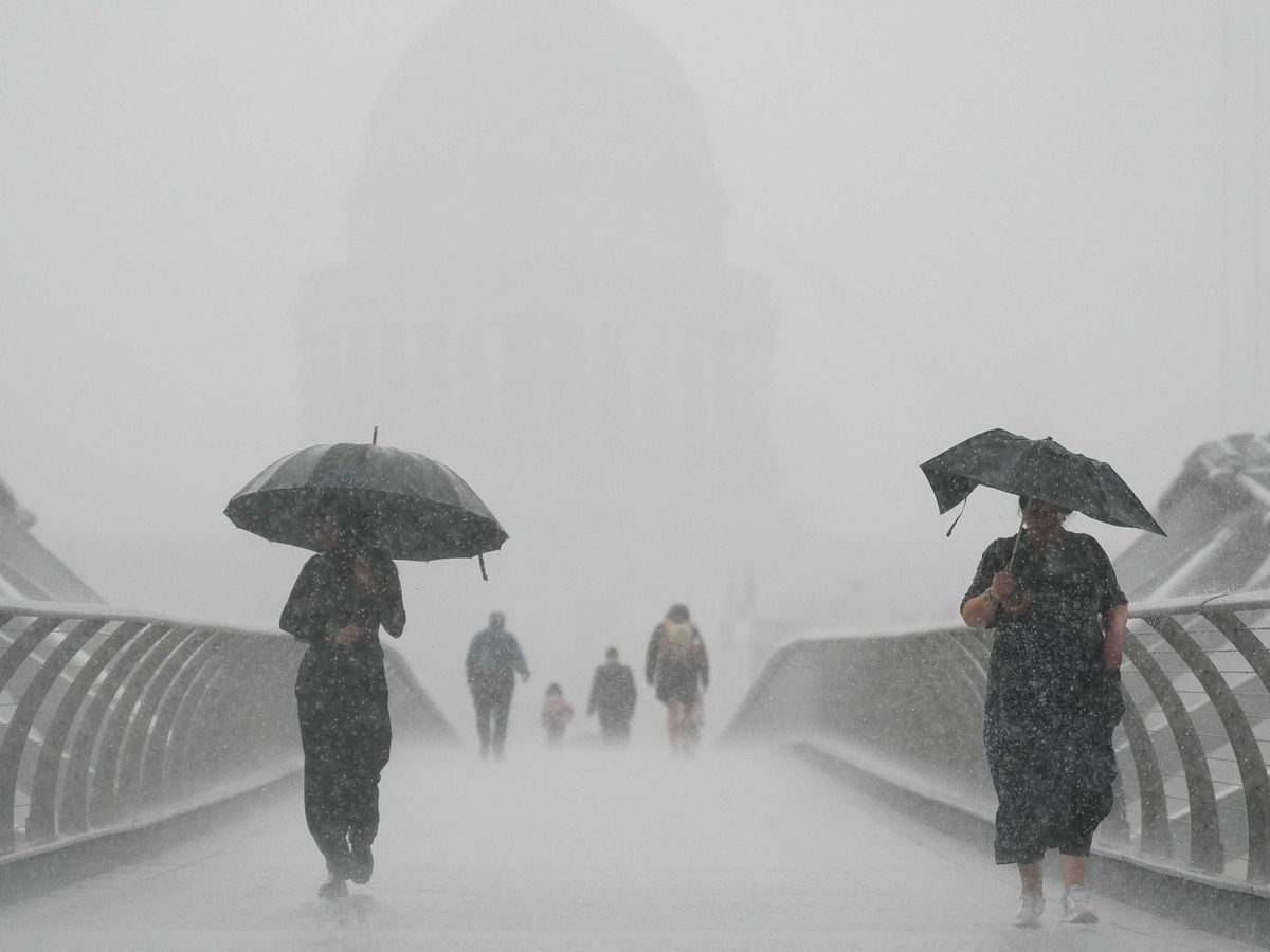 People with umbrellas walking in the rain on Millennium Bridge, London. After weeks of sweltering weather, which has caused drought and left land parched, the Met Office’s yellow thunderstorm warning forecasts torrential rain and thunderstorms that could hit parts England and Wales (Victoria Jones/PA)