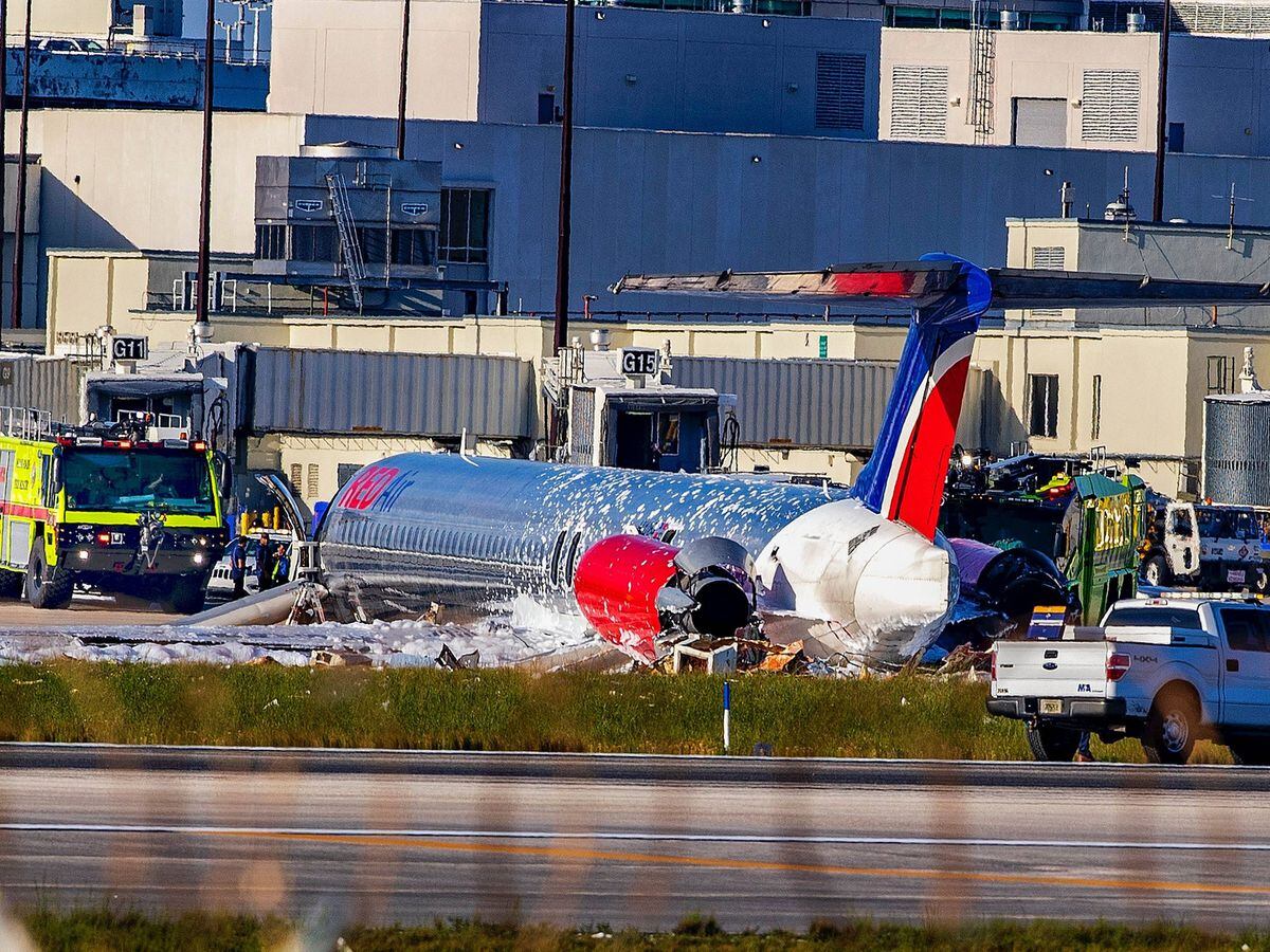 Firefighting units are seen next to a Red Air plane that caught fire after the front landing gear collapsed upon landing at Miami International Airport