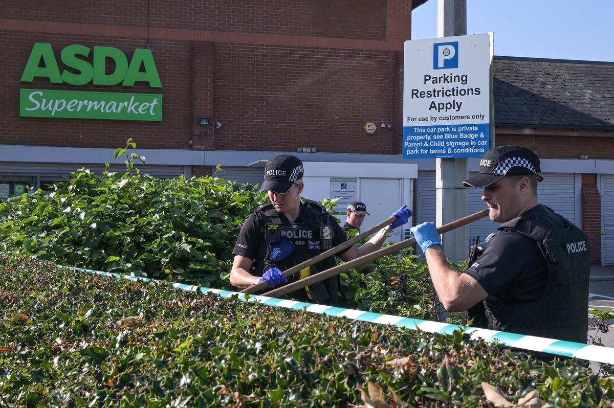 Police search hedges outside the Asda after the stabbing. Photo: SnapperSK