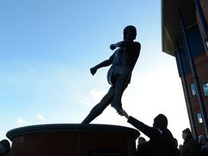 A fan touches the foot of the Tony Brown statue outside The Hawthorns the home stadium of West Bromwich Albion.