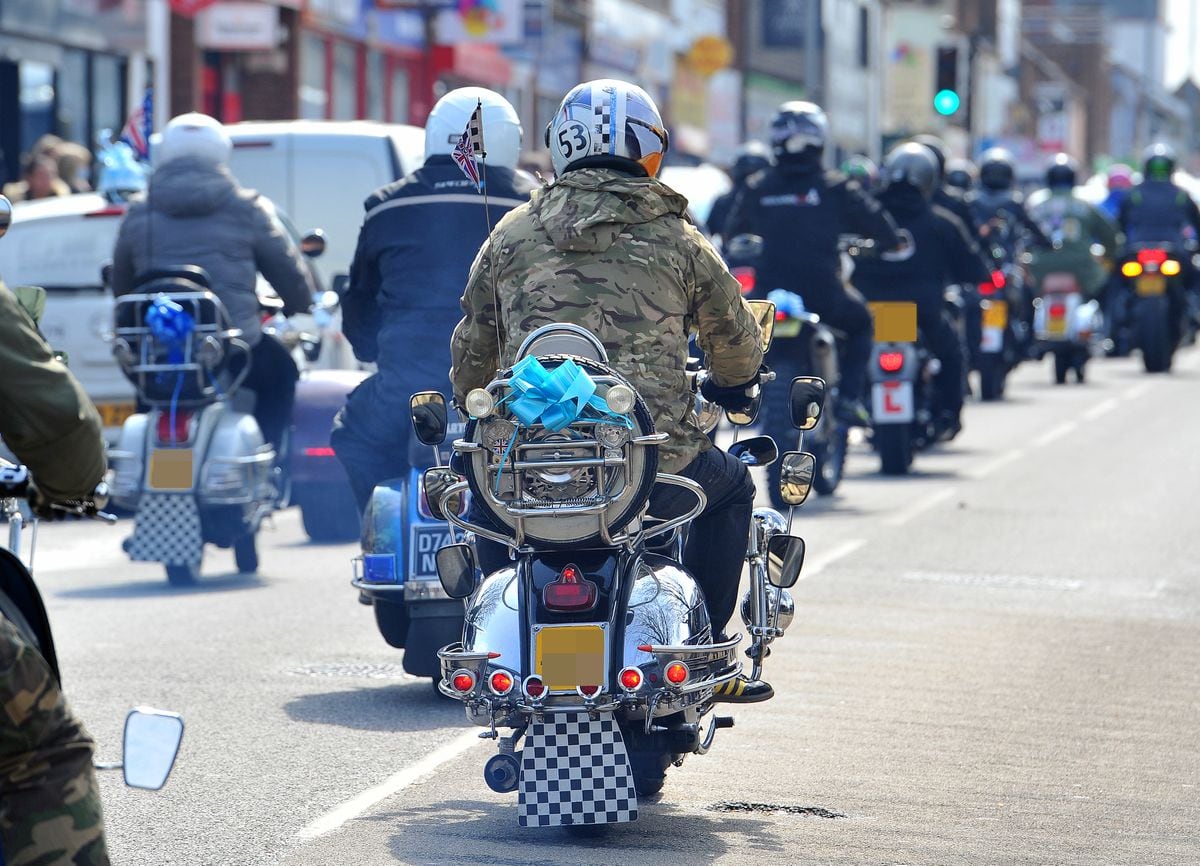 Motorcylists bearing blue ribbons accompany the funeral procession