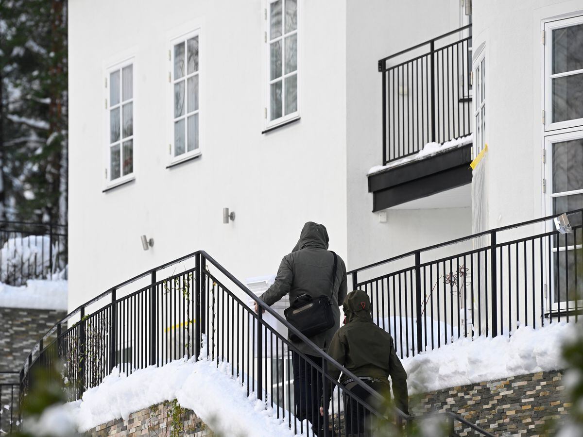 Two unidentified people are seen approaching a house where the Swedish security service allegedly arrested two people on suspicion of espionage in a predawn operation in Stockholm on Tuesday
