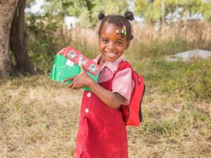 A girl in Zimbabwe smiling with her Operation Christmas Child box of presents